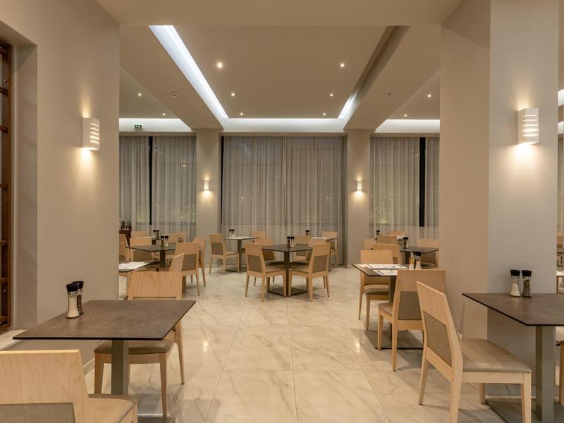 Modern, bright dining area with wooden tables and chairs in a hotel.