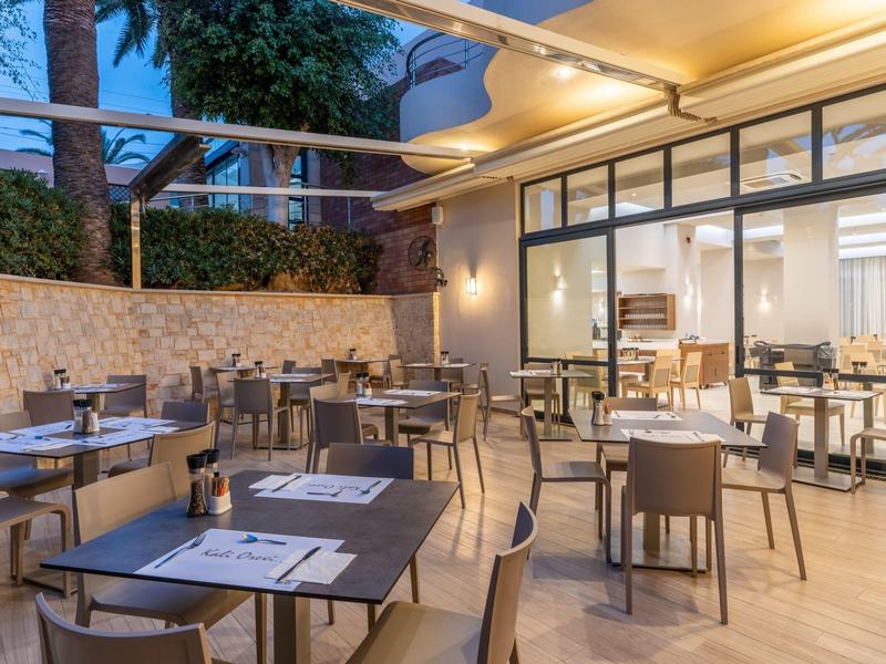 Open dining area with modern tables and chairs adjacent to an indoor space with large glass windows.