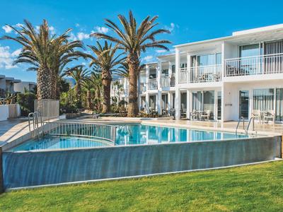 Piscina moderna dell'hotel con palme e edificio a due piani sullo sfondo in una giornata di sole.
