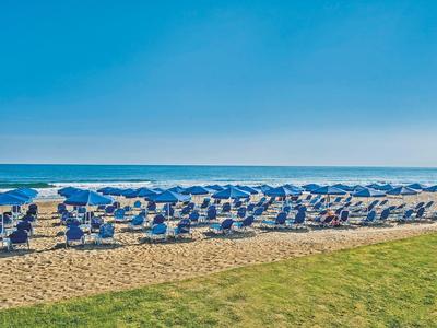 Rangées de tentes blanches de plage avec des parasols bleus sur la plage de sable près de la mer