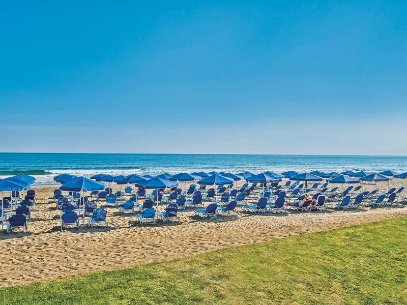 Rangées de tentes blanches de plage avec des parasols bleus sur la plage de sable près de la mer