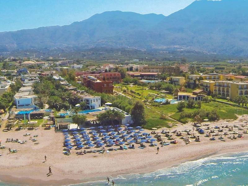 Station balnéaire avec parasols, chaises longues et montagnes en arrière-plan.