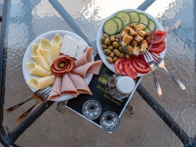 Due piatti con formaggio, affettati, verdure e olive serviti su un tavolo di vetro.