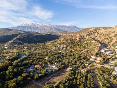 Paesaggio con valli verdi, case sparse e montagne innevate sullo sfondo.