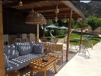 Accogliente area esterna con divano, sedie e tavolo in legno sotto una copertura.