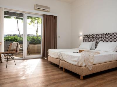 Moderne hotelkamer met twee eenpersoonsbedden, houten vloer en toegang tot een balkon met zitgelegenheid.