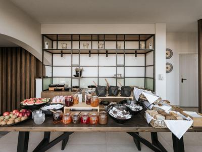 Buffet con diversos productos horneados, vasos y decoración en una habitación de hotel moderna.