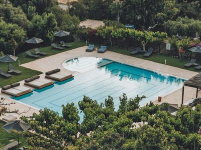 Piscina all'aperto con lettini e ombrelloni in un ambiente verde e boscoso