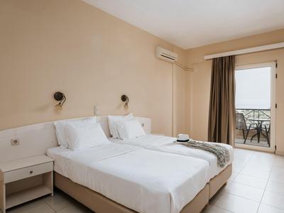 Camera d'hotel luminosa con due letti singoli e balcone con vista esterna.