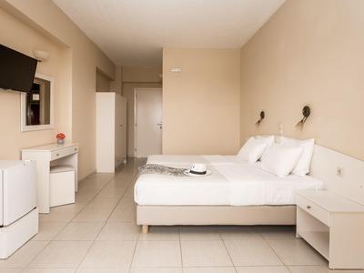 Camera d'albergo luminosa con letto grande, mobili bianchi e televisore a schermo piatto montato a parete.