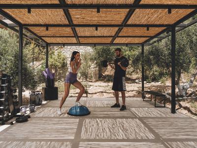 Dos personas entrenando en un área exterior cubierta con equipo de fitness.