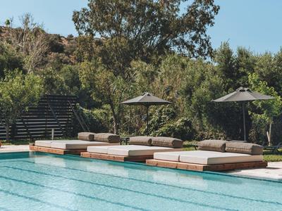 Poolbereich mit Sonnenliegen und Sonnenschirmen neben einem klaren blauen Wasserbecken.