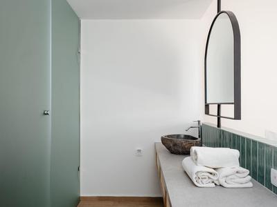 Bagno minimalista con porta in vetro verde, lavabo con piastrelle verdi e asciugamani