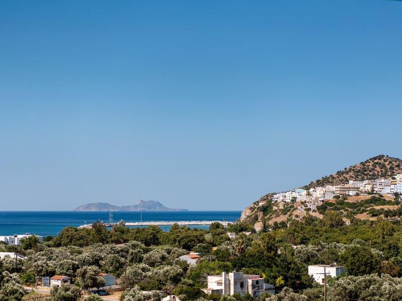 Vista di una città costiera con alberi verdi e scogliere sotto un cielo azzurro limpido.