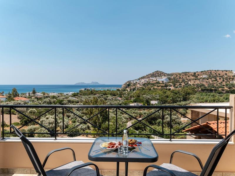 Balcone con tavolo e due sedie con vista sul mare e sulle colline sotto un cielo limpido