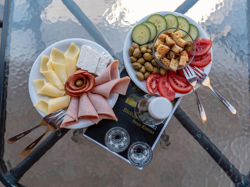 Due piatti con formaggio, affettati, verdure e olive serviti su un tavolo di vetro.