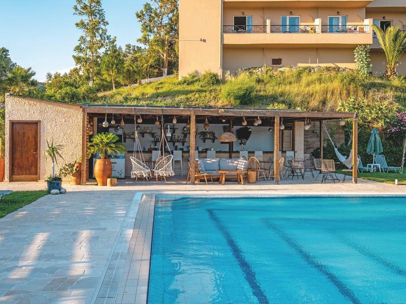Piscina di fronte a un edificio con terrazza e giardino in ambiente soleggiato
