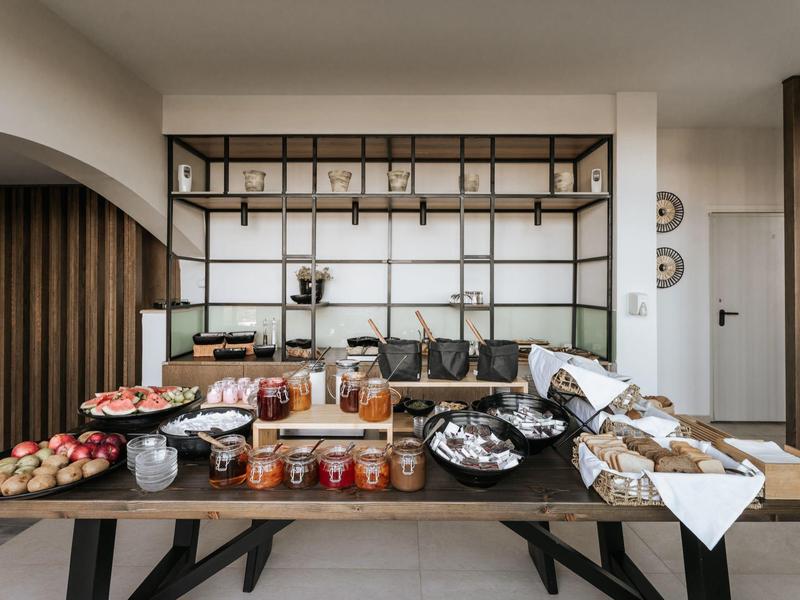 Buffet con vari tipi di pane, creme spalmabili e bevande in un ambiente alberghiero moderno