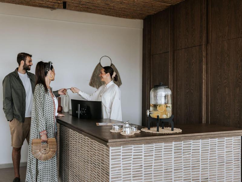 Una coppia fa il check-in alla reception dell'hotel, il personale li accoglie cordialmente.