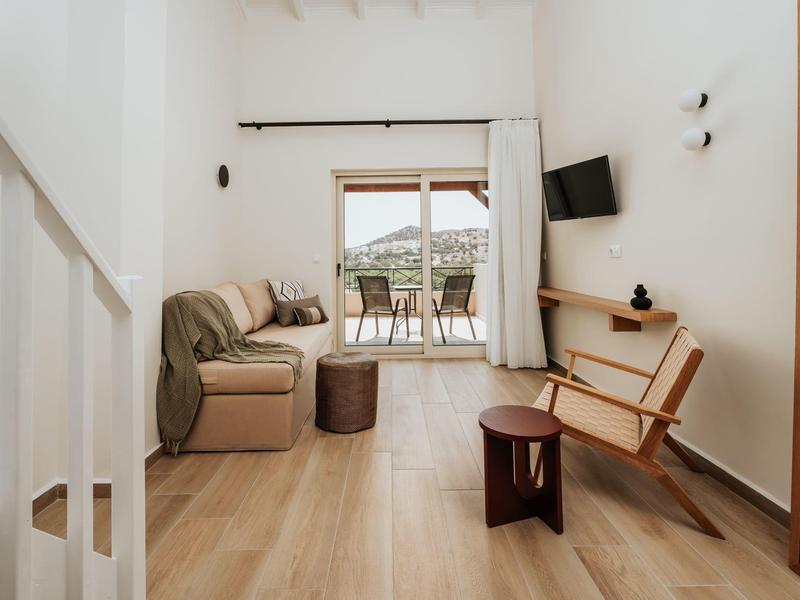 Soggiorno moderno con zona salotto, mobili in legno e accesso al balcone con vista