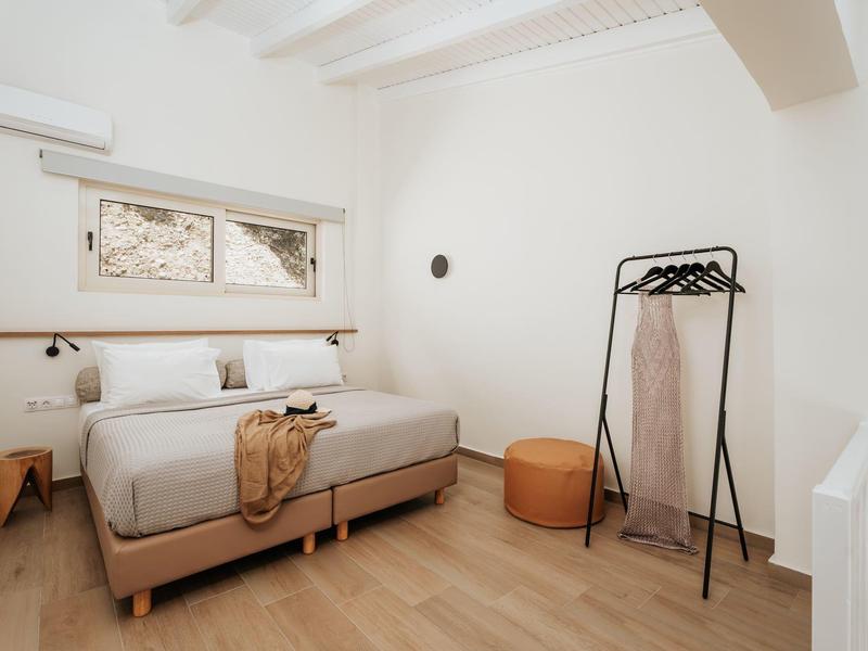 Camera da letto luminosa e moderna con letto matrimoniale, pavimento in legno e attaccapanni semplice.