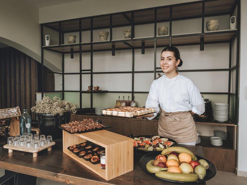 Personale dell'hotel nell'area dessert con vari dolci e frutta sul tavolo.