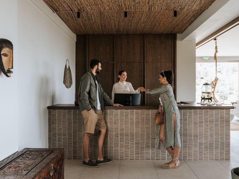 Una coppia parla con un receptionist alla reception di un hotel.