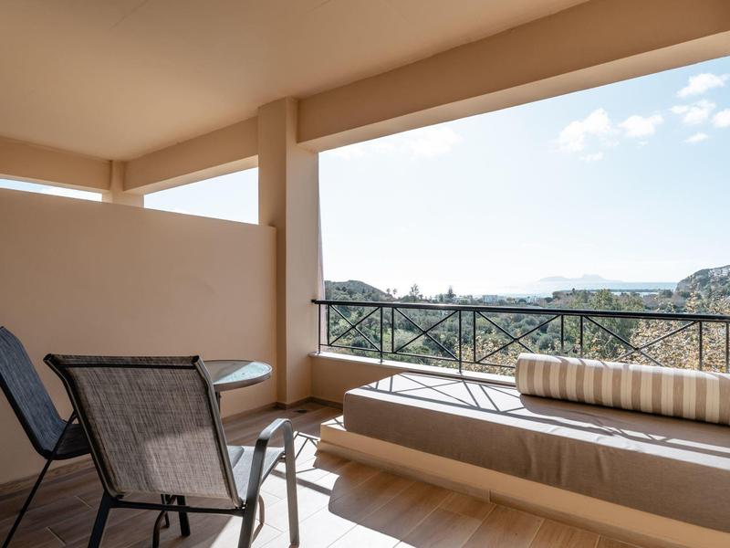 Balcone con sedie e lettino con vista sul paesaggio circostante sotto un cielo sereno.