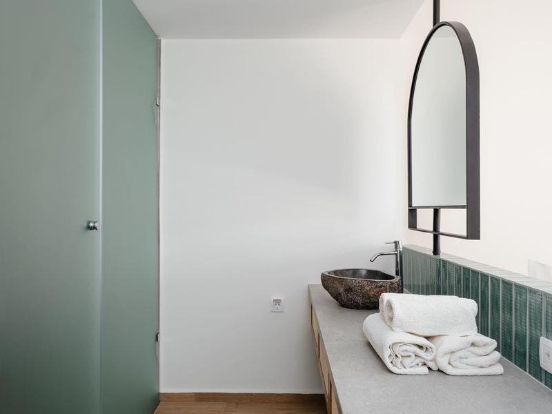 Bagno minimalista con porta in vetro verde, lavabo con piastrelle verdi e asciugamani