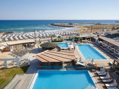 Veduta di un resort con più piscine, lettini, spiaggia e mare sullo sfondo.