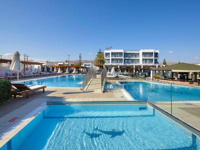 Grande piscina dell'hotel con lettini, ombrelloni e cielo azzurro limpido.