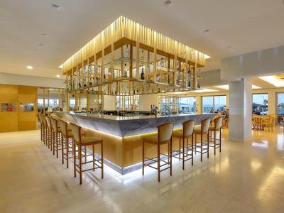 Bar moderna con sgabelli di legno e bancone illuminato in un elegante ristorante dell'hotel.