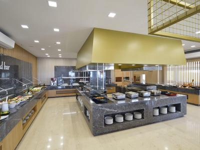 Postazione buffet moderna con bar insalate e area cucina in un ristorante d'hotel.