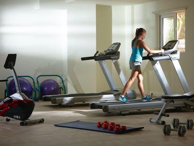 Donna che cammina su un tapis roulant in una palestra luminosa con attrezzature da palestra.