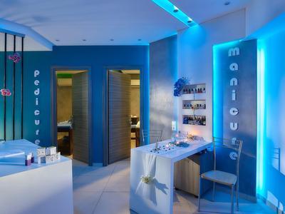 Sala benessere moderna con tavoli per pedicure e manicure sotto una luce blu rilassante.
