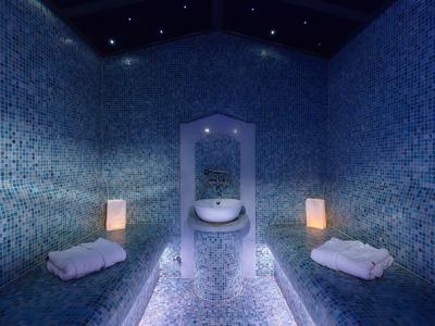 Una stanza di bagno turco elegante con piastrelle a mosaico, illuminazione soffusa e asciugamani.