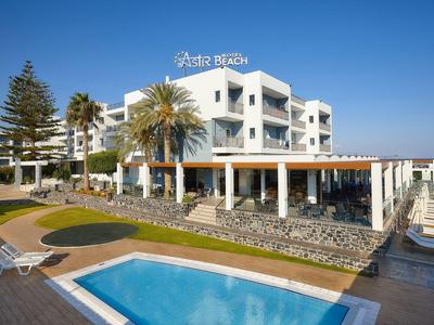 Edificio moderno dell'hotel con piscina all'aperto, lettini e palme sotto un cielo blu sereno.