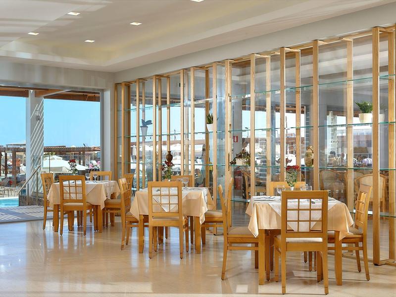 Zona pranzo moderna in hotel con divisori dorati e tavoli in legno con sedie.