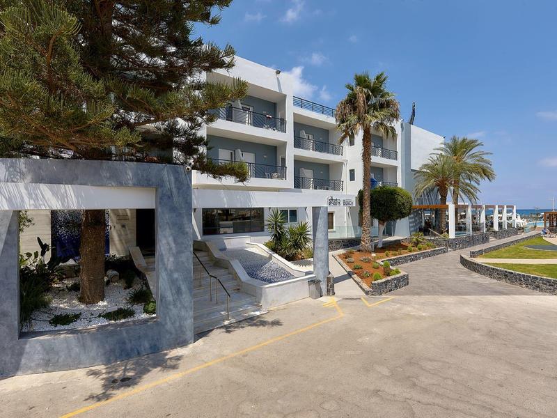 Complesso alberghiero moderno con palme e giardino ben curato in una giornata di sole.