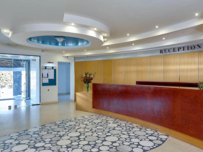 Reception di hotel moderna con banco rosso e grande finestra.