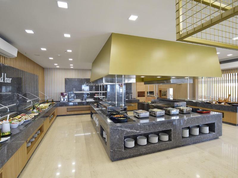 Postazione buffet moderna con bar insalate e area cucina in un ristorante d'hotel.