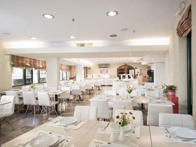 Restaurante moderno y luminoso con sillas blancas y mesas preparadas, soleado y acogedor.