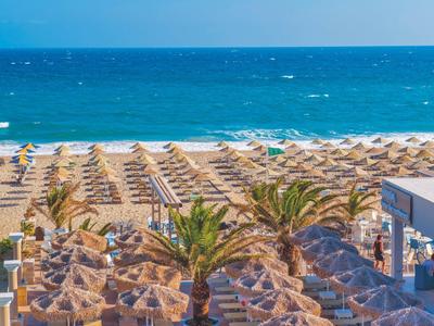 Playa con muchas sombrillas y vista al mar azul en destino vacacional.
