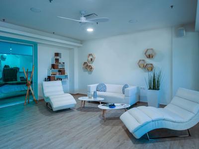 Modern eingerichtetes Wohnzimmer mit weißen Lounge-Sesseln und einem Sofa in neutralen Farben.