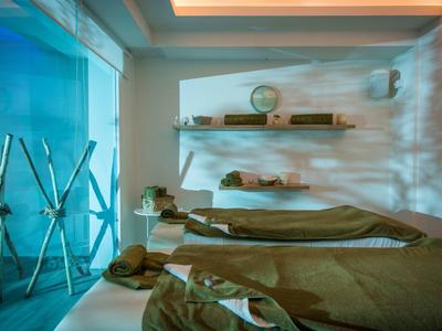 Sala de relajación con dos camillas y luz azul tranquilizadora en el spa de un hotel.