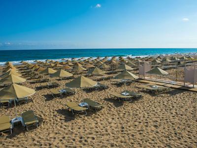 Leerer Sandstrand mit vielen Sonnenschirmen und Sonnenliegen am Meer