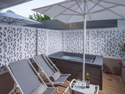 Moderner Außenbereich mit Liegestühlen, Sonnenschirmen und Whirlpool in einem Hotel.