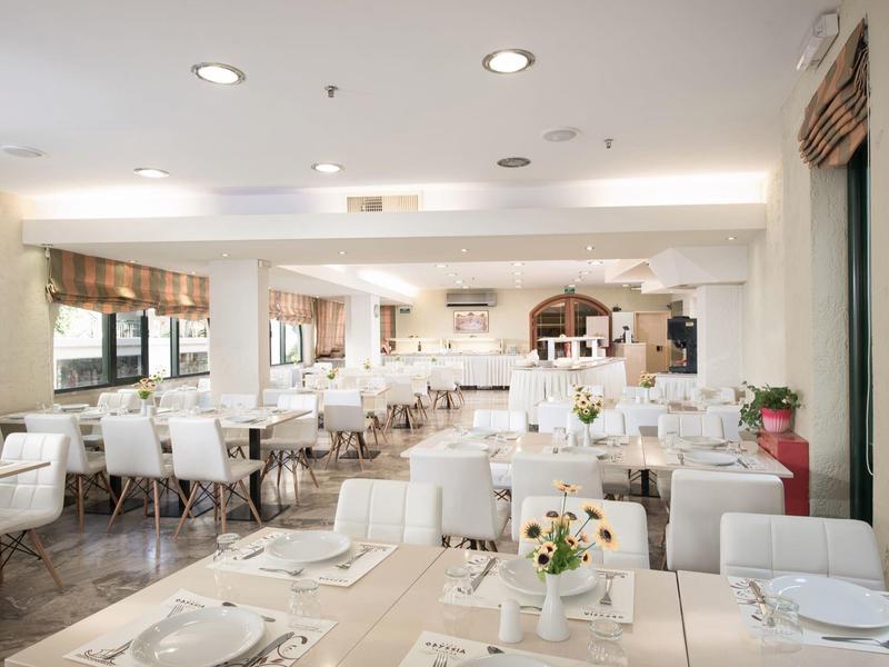 Restaurante moderno y luminoso con sillas blancas y mesas preparadas, soleado y acogedor.