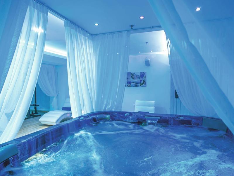 Jacuzzi en una habitación moderna y luminosa con cortinas blancas y ambiente relajante.