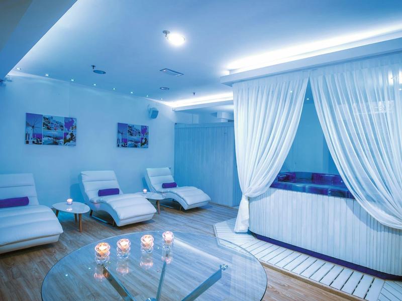 Área de relajación con tumbonas blancas, cortinas y luz suave en un hotel.